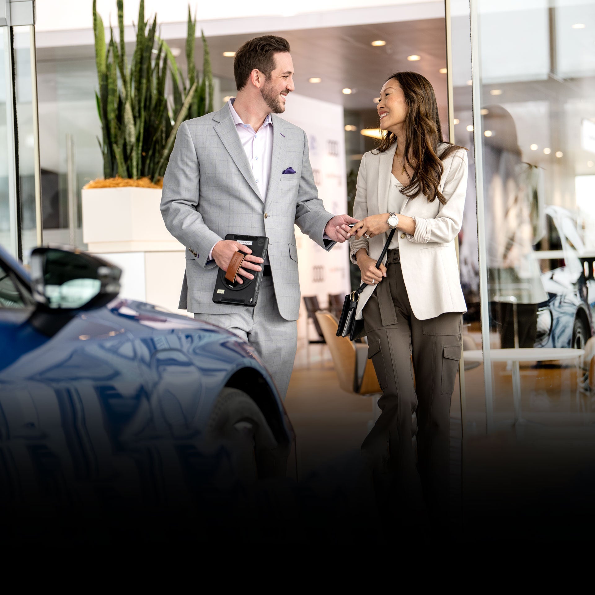 Audi salesman wearing grey suit jacket handing keys to customer